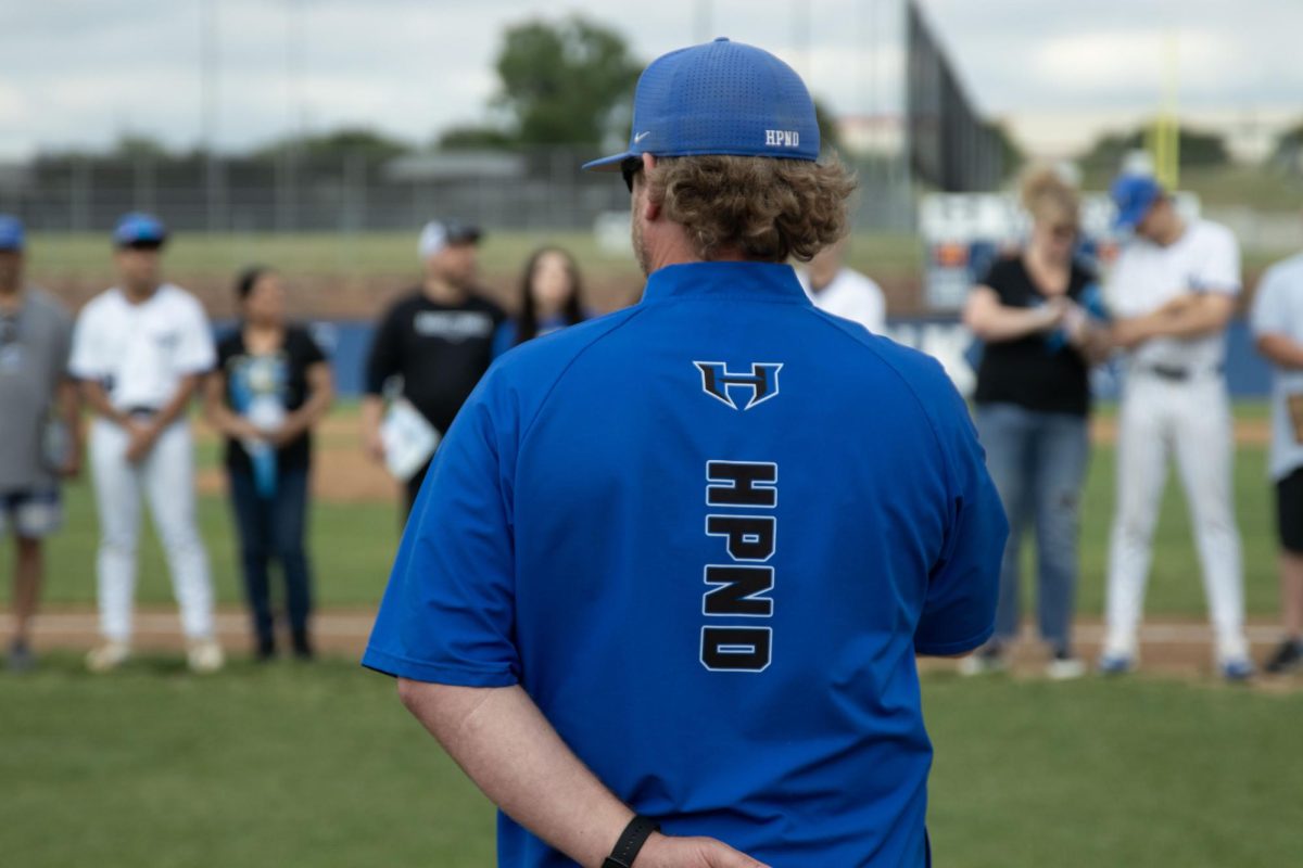Head coach Corey Farra watches the seniors get announced during the senior game against Flower Mound April 23. The team lost the game 3-2.