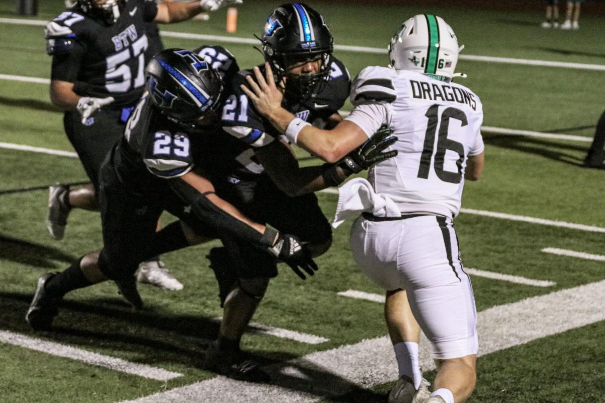 Linebacker Miguel Cachutt and outside linebacker Aaron Mccardell tackle the Southlake Carroll quarterback during the third quarter. The Hawks did not score during the third quarter, which ended with a score of 52-13.