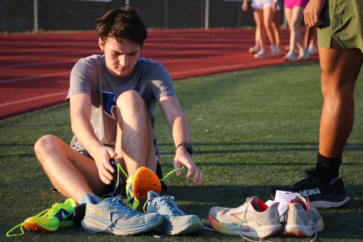 Sophomore Justice Whitfield ties his shoelaces at a practice on Oct. 10. The cross country team did sprints on the track in preparation for the district championships tomorrow. “I’m feeling confident about the district championships,” Whitfield said. “I’m hoping that I can place in the top 10.” 