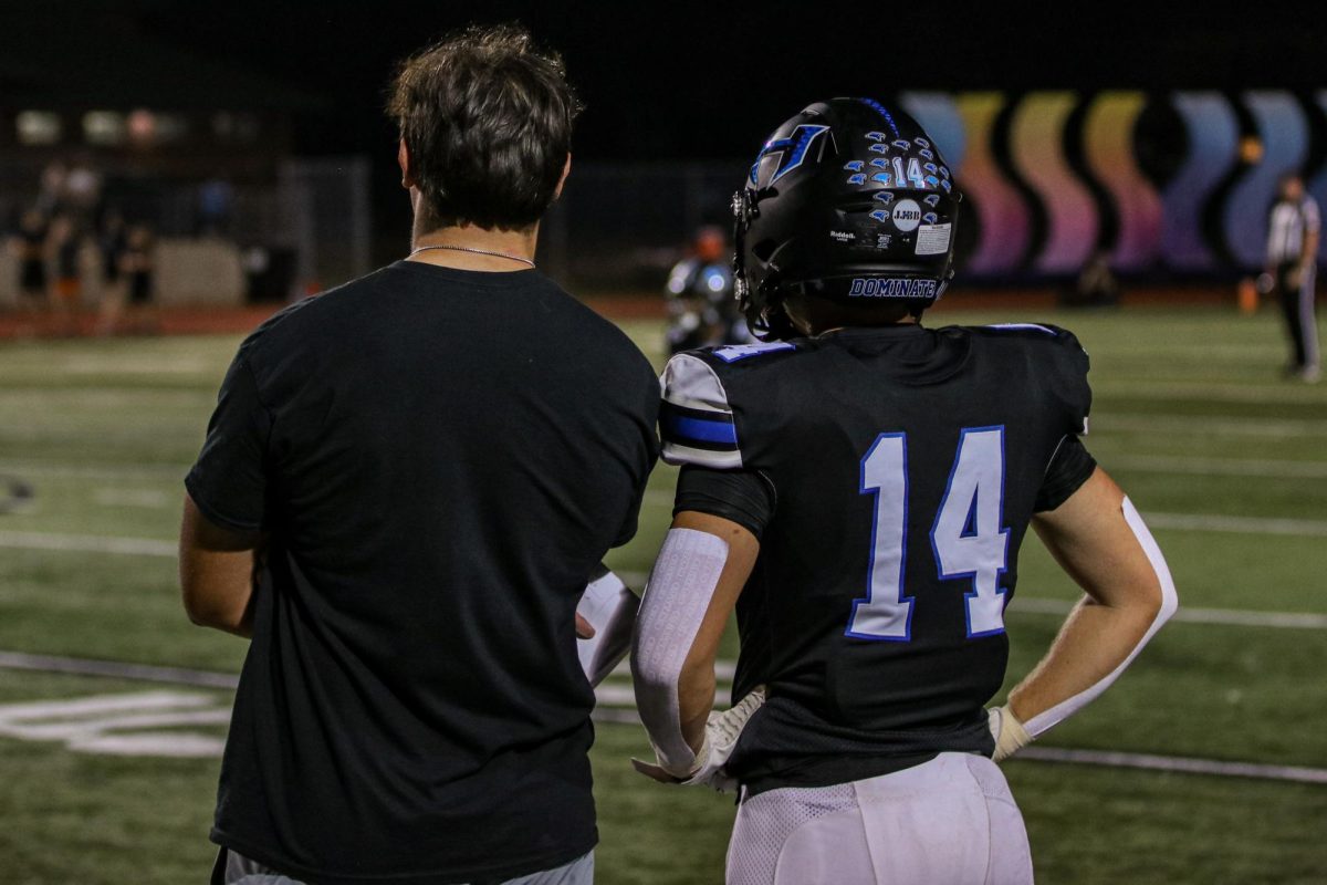 Lindmark (left) and Luke (right) watch the game from the sidelines together during the team's game against Guyer on Oct. 11. Both Luke and Lindmark have taken the same amount of AP classes and helped each other deal with the stresses of school.