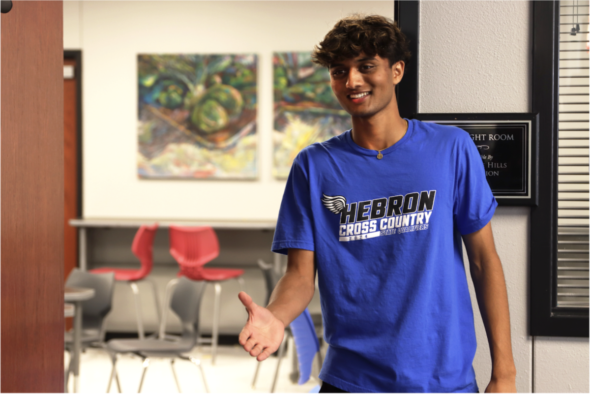 Senior Kavish Patel gives out his hand for a handshake while greeting club members. is the president of the entrepreneurship club and owner of his own business. 