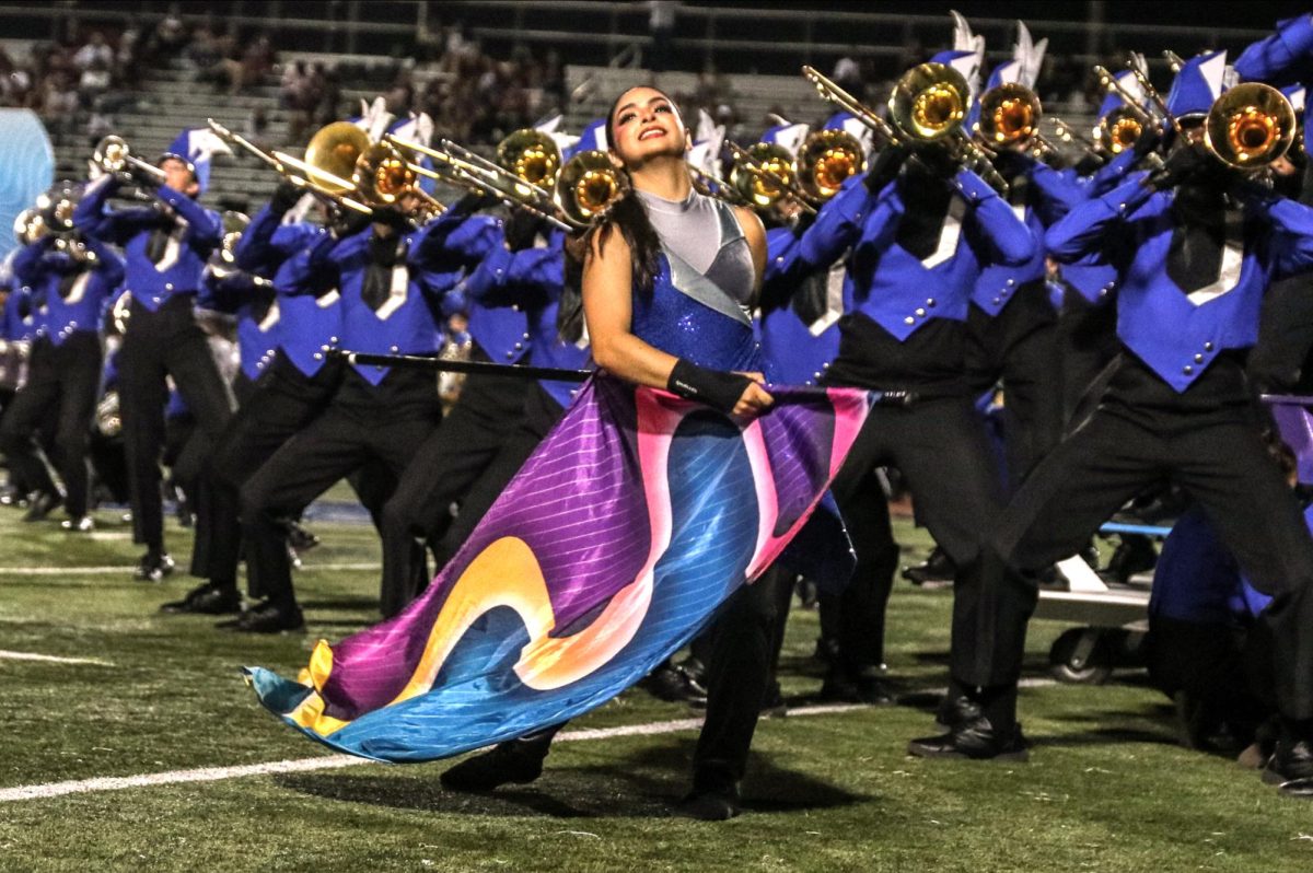 Senior Michelle Vasquez performs a flag routine during the band’s marching show “Amorphous.” The color guard will hold a clinic for children in grades K-8 on Dec. 7 at 8:30 a.m. at the main campus gyms.