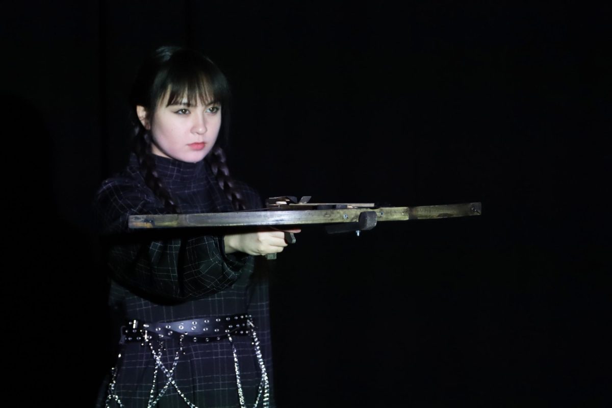 Senior Lucy Ward poses during the promotional shoot of the production. Her character, Wednesday, uses a crossbow when she meets her boyfriend, Lucas Bieneke. 